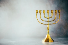Golden Hanukkah Menorah On Grey Background. Jewish Holiday Banner With Copy Space. Ancient Ritual Religious Candle Menorah