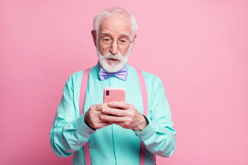 Photo of cool stylish grandpa holding telephone hands read email freelancer good news wear specs mint shirt suspenders violet bow tie pants isolated pink pastel color background