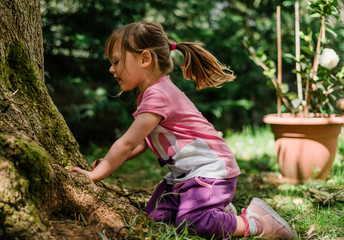 Little girl enjoying the nature and exploring the garden in a sunny day