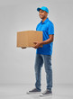 © Syda Productions - mail service and shipment concept - happy indian delivery man with parcel box in blue uniform over grey background