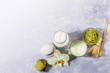 © SeNata - Set of matcha latte tea glass, bottle of milk, accessories and ingredients, spa stones, Orchid flower on grey backdrop.