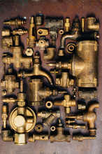 Brass Scrap Metal: Taps, Tees, Plugs And Various Plumbing Parts, Spare Parts. Against The Background Of A Copper Sheet. Close-up.