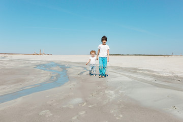 two real brother and sister run on the sand on a summer sunny day