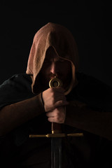 medieval Scottish man in mantel with sword  in dark isolated on black