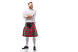 smiling Scottish redhead man in red kilt with crossed arms on white background
