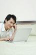 © ImageHit - Man smiling while using laptop in the bedroom