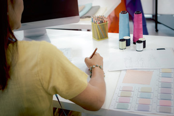 Woman fashion designer in studio, seamstress working at workplace in fashion workshop, female designer drawing pencil sketches, working with crafting tools and sewing accessory