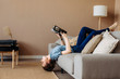 Girl reading a book lying on the couch upside down in the living room at home, romantic mood. Lifestyle