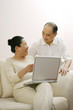 © ImageHit - Senior woman talking to senior man while using laptop