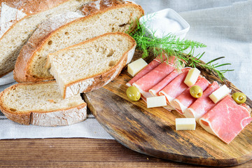 Wall Mural - Slices of jamon, bread integral, olives and cheese on the wooden cutting board.