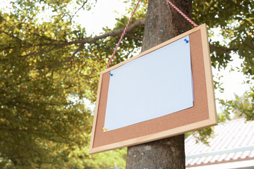 white paper post blank text message note on notice board hanging on tree in garden