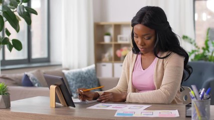 business, remote job and technology concept - african american female ui designer with tablet pc computer working on user interface design at home office