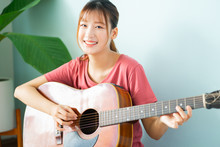 Young Asian Woman Learning Guitar At Home