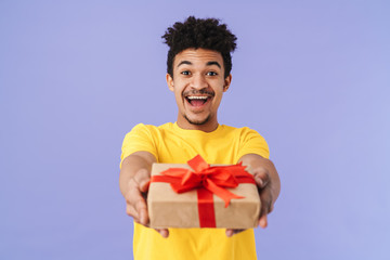 Wall Mural - Photo of happy african american man holding out gift box and smiling