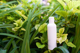 Fototapeta Sypialnia - Clean body lotion bottle on green nature background.