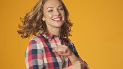 Poster - Young happy positive girl isolated over yellow wall background dancing