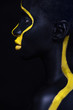 © Mike Orlov - Woman with black body paint. Cheerful young african girl with art bodypaint. An amazing model with yellow makeup. Closeup face.