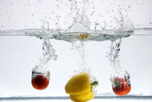 Two Red Tomatoes And Yellow Pepper Are Falling Into The Water The Great Splash And Bubbles