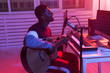 © satura_ - African american professional musician recording guitar in digital studio at home, music production technology concept.