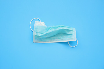 Disposable surgical face mask on blue background protection against COVID-19 coronavirus. Healthcare and medical concept