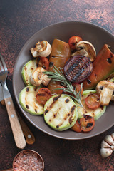 Wall Mural - Grilled vegetables (zucchini, cherry tomatoes, onions, champignons, bell peppers) served in a plate with rosemary and sea salt on a dark vintage background. Top view. Copy space. Vertical