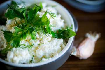 salted homemade cottage cheese with garlic and herbs in a bowl