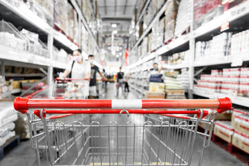 The empty red shopping cart in supermarket with blurred background.