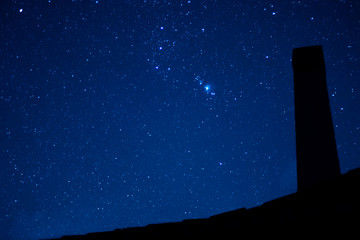 Image of the starry sky with the silhouette of an ancient fireplace 