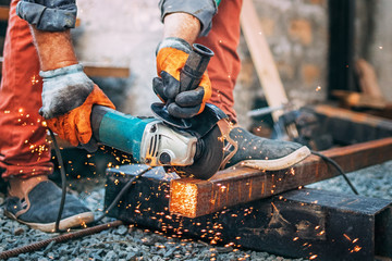 Wall Mural - a man is sawing metal with an angle grinder.