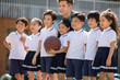 © Blue Jean Images - Foreign teacher and children playing basketball in playground