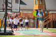 © Blue Jean Images - Foreign teacher and children playing basketball in playground
