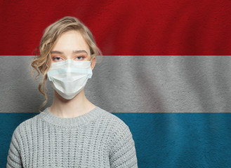 Wall Mural - Young woman wearing a face mask with national Luxembourg  flag. Flu epidemic and virus protection concept