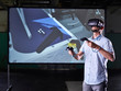 © Westend61 - Man wearing VR glasses and using joysticks in virtual training class