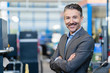 © Westend61 - Portrait of successful businessman in shop floor of company, with arms crossed
