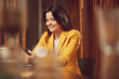 © Westend61 - Smiling businesswoman wearing yellow suit sitting at desk in office using cell phone