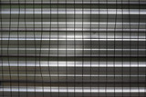 Fototapeta Sypialnia - metal grid in the form of squares . metal gray wall with horizontal lines behind the grid