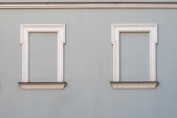 Gray building wall with 2 window frames (placeholders) bricked up.  Being in isolation; hidden, silent and secured area.