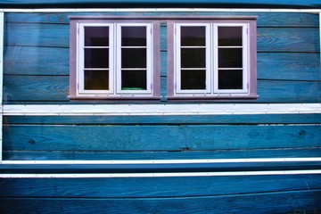 two windows on a blue wooden wall