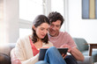 © Westend61 - Couple sitting on couch at home using tablet