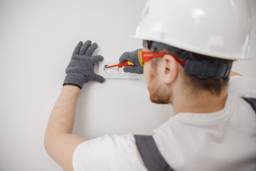 Wall Mural - Sockets outlet install Electrician man builder working at home