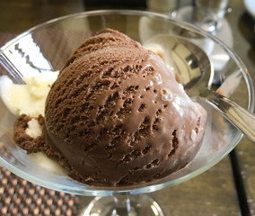 chocolate and cream ice cream in a glass cup on the table