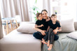 © Kateryna - A portrait of an attractive caucasian young mother and her two beautiful daughters. They are sitting on the sofa at home in casual stylish clothes hugging and smiling in a positive mood
