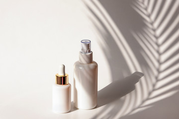 Wall Mural - Cosmetic tonic and serum in blank packages on a background of white wall with palm leaves shadows. Natural skincare products concept.