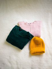 folded sweaters and beanie on white background