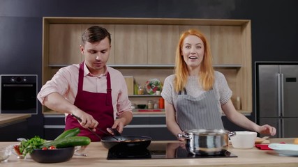 Wall Mural - Cooking show hosts chefs, male and female, cooking meat. Morning TV cooking programme. Shot on ARRI Alexa Mini