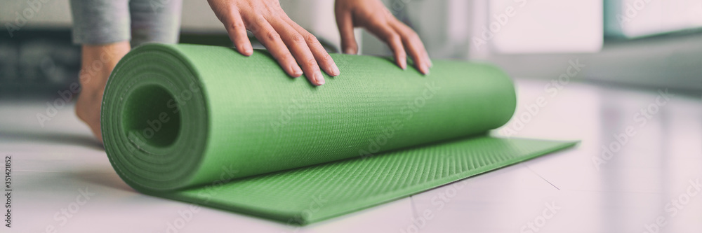 Home meditation woman rolling yoga exercise mat in living room for pilates workout online class banner panoramic apartment lifestyle. - obrazy, fototapety, plakaty 