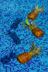 Pineapple Floating In blue Water In Swimming Pool. Tropical vacation concept. Exotic tropical background.