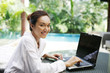 © ImageHit - Woman smiling at the camera while using laptop