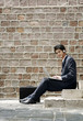 © ImageHit - Businessman with headphones sitting on stairway using laptop
