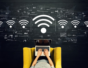 Wall Mural - Wifi theme with person using a laptop in a chair